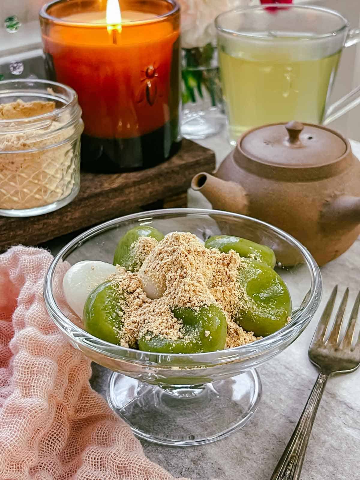 Matcha and plain white Shiratama Dango topped with kinako in a dessert glass, served with green tea poured from kyusu Japanese tea pot.
